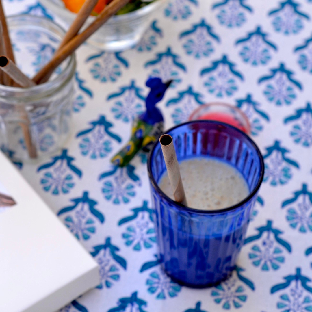 Blue glass with a straw on a patterned tablecloth