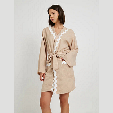 Woman wearing a beige robe with lace trim on a white background